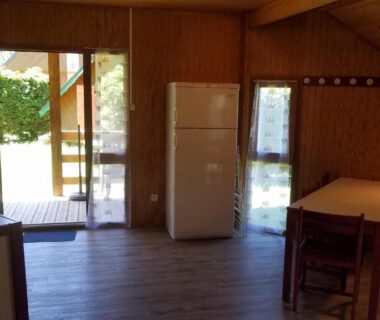 Intérieur de bungalow en bois avec coin repas et réfrigérateur au Domaine du Lac Chambon