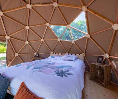 Intérieur du dôme avec lit et structure en bois au Dôme insolite du parc régional du Pilat