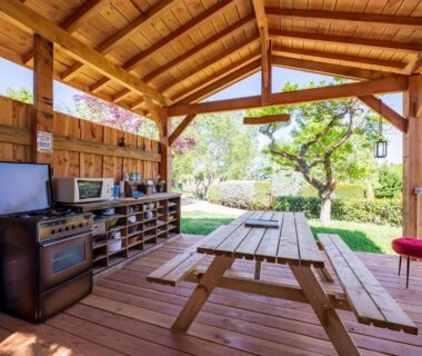 Espace extérieur couvert avec coin cuisine et table de pique-nique au Dôme insolite du parc régional du Pilat