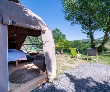 Extérieur du dôme avec chaises longues et lit visible dans le Dôme insolite parc régional du Pilat