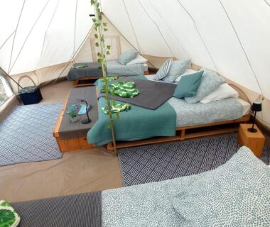 Intérieur de tente avec lits sur plateforme et coussins au Dordogne Glamping & Camping
