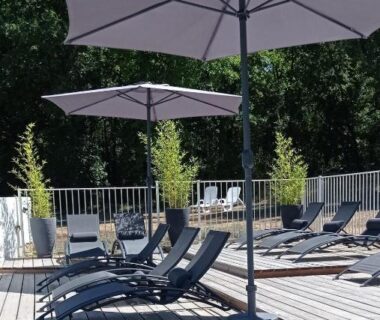 Terrasse de piscine avec transats et parasols au Dordogne Glamping & Camping