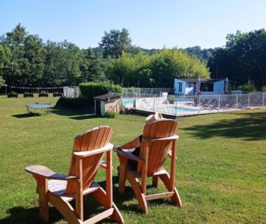 Pelouse avec chaises en bois et piscine au Dordogne Glamping & Camping
