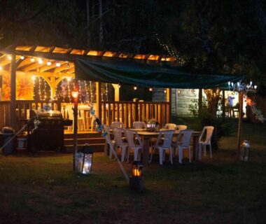 Terrasse couverte éclairée avec tables et chaises au Dordogne Glamping & Camping