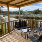 Terrasse couverte avec mobilier extérieur donnant sur l'étang au camping Douce Escale