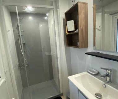 Salle de bains avec cabine de douche vitrée et lavabo au camping Douce Escale
