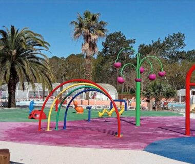 Aire de jeux aquatique colorée avec palmiers au camping Douce Escale