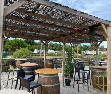 Terrasse couverte avec tables en tonneau au camping Douce Escale