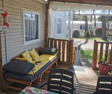 Terrasse couverte avec banquette et table de repas au camping Dunes 209