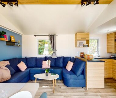 Séjour lumineux avec canapé d'angle bleu dans le mobil-home EA Votre séjour 4 étoiles