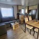 Salon avec canapé, coin repas et kitchenette dans le mobil-home Eden 1708