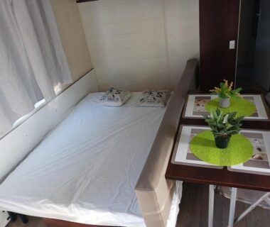 Intérieur du mobil-home avec lit convertible et table du camping El sol
