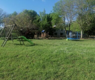 Prairie avec aire de jeux balançoires et trampoline au Emplacement tente camping car