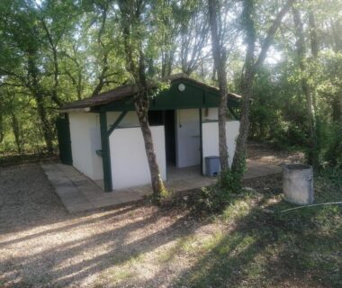 Bloc sanitaire ombragé au cœur des bois de l'emplacement tente camping car