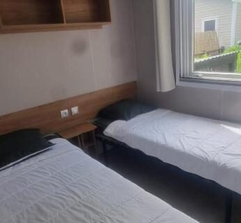 Chambre avec deux lits et fenêtre dans le mobil-home Envie d'évasion