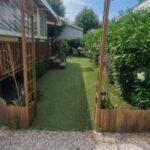 Allée de jardin avec arche et mobil-home au camping Envie d'évasion