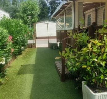 Allée en gazon synthétique avec terrasses et jardinières au camping Envie d'évasion