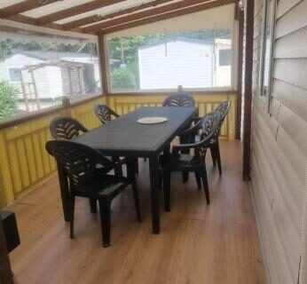 Terrasse couverte avec table et chaises du camping Envie d'évasion