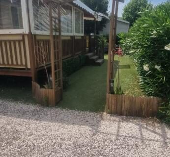 Allée gravillonnée et mobil-home avec terrasse en bois au camping Envie d'évasion