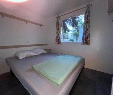 Chambre intérieure avec lit double et fenêtre dans le bungalow Escale Nature F14 au camping Le Ried