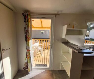 Intérieur avec kitchenette et terrasse en bois du bungalow Escale Nature Bungalow F14 pour 4 au camping Le Ried