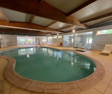 Piscine couverte avec chaises longues au camping Le Ried pour le bungalow Escale Nature Bungalow F14