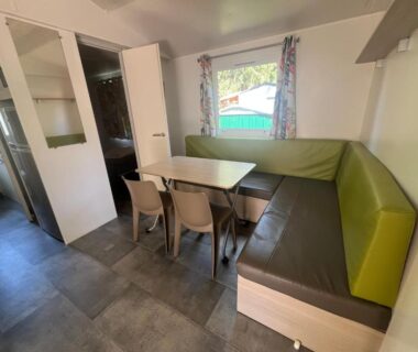 Intérieur coin repas avec banquette et table dans le bungalow Escale Nature F14 au camping Le Ried