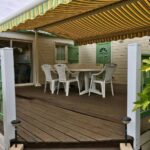 Terrasse couverte avec table et chaises sous store rayé de l'Escale vendéenne