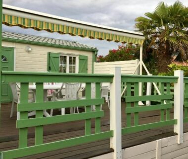 Terrasse de mobil-home avec store rayé et palmiers de l'Escale vendéenne