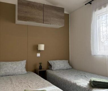 Intérieur chambre avec deux lits table de nuit et serviettes dans le mobil home Escapade au Ferret