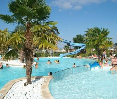 Piscine extérieure avec toboggan et palmiers au camping Etxe ona au bord de l'eau