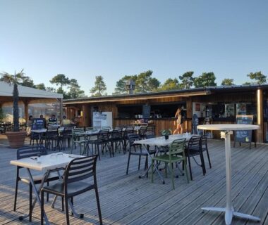 Terrasse en bois avec tables et chaises au camping Etxe ona au bord de l'eau