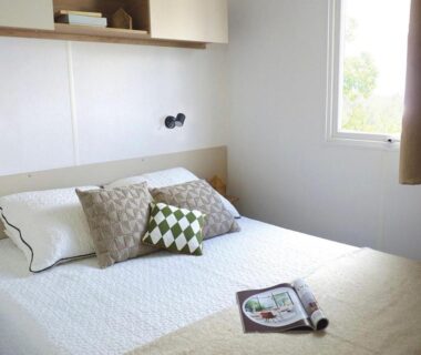 Chambre intérieure avec lit double coussins et fenêtre dans l'Évasion Lodge
