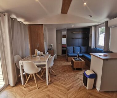 Séjour lumineux avec salon et coin repas donnant sur terrasse dans l'Évasion Lodge