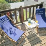 Terrasse en bois avec deux chaises longues et petite table à Evasion Normande