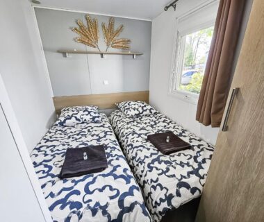 Chambre avec deux lits et serviettes dans le mobil-home Evasion Normande