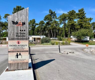 Entrée avec panneau en bois et allée du camping Évasion famille Dune Blanche