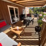 Terrasse en bois avec salon et table extérieure de l'hébergement Evasion premium tout confort