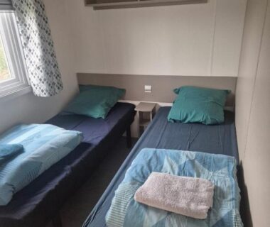 Chambre avec deux lits simples et serviettes dans le FMLODGE mobil Inès au sable du mdi