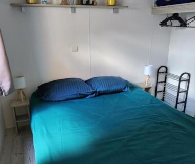 Chambre avec lit double étagère et lampes dans le FMLODGE mobil home Le coin paradis