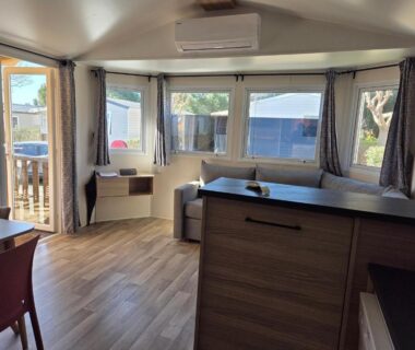 Intérieur du mobil home avec coin salon et kitchenette du FMLODGE mobil home soleil et sieste