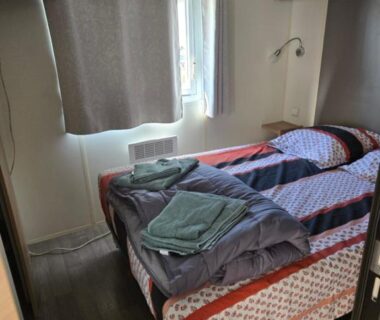Chambre avec deux lits et serviettes dans le FMLODGE-mobilhome olivier au sable du midi