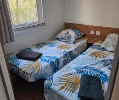 Chambre avec deux lits simples et fenêtre dans le FMLODGE sables du midi mobilhome le reposoir