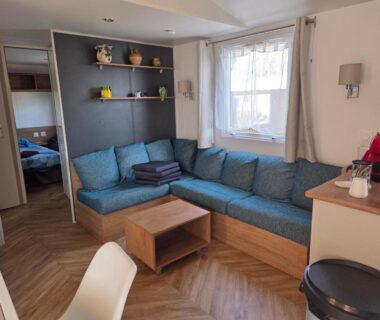 Salon avec banquette d'angle bleue et table basse dans le mobilhome FMLODGE sables du midi le reposoir