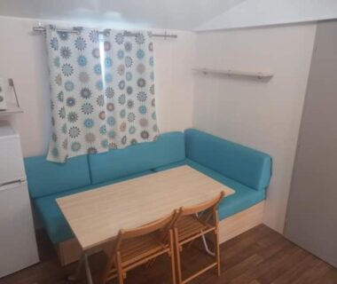 Coin repas avec banquette bleue et table dans le locatif Famille Peeters