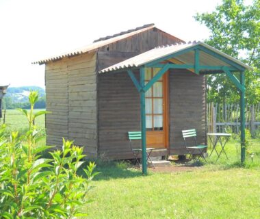 Cabane en bois avec terrasse et chaises dans le jardin à la Ferme équestre Les Chevaliers