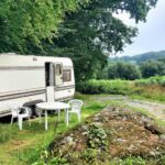 Dans la campagne normande caravane garée sur pelouse avec table et chaises au Fern Meadow Caravan
