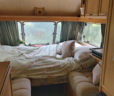 Intérieur de caravane avec lit, rangements et rideaux dans la Fern Meadow Caravan