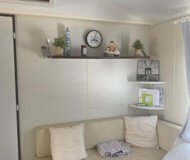 Coin salon avec banquette étagère et horloge dans le Flo mobil home camping Poney trois étoiles