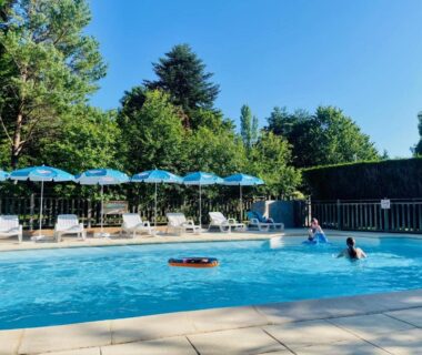 Piscine extérieure avec parasols et transats au Flower Camping La Pibola